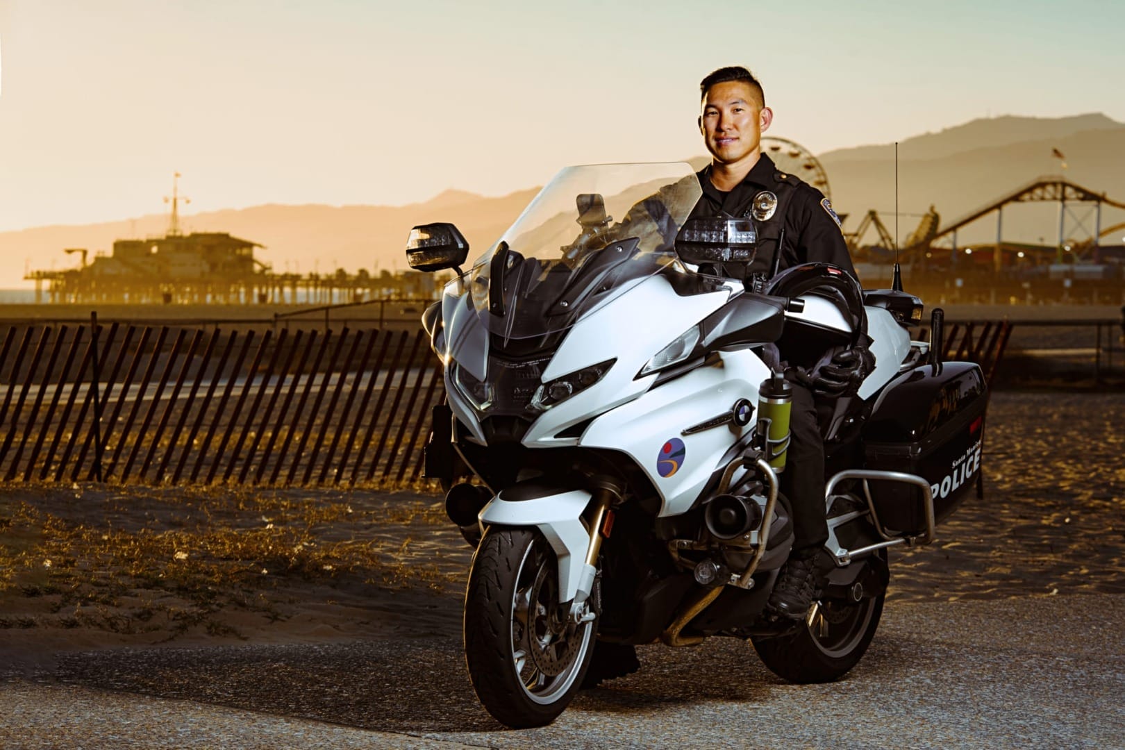 Police officer on motorcycle at sunset with amusement park in the background.