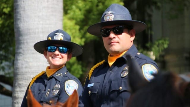 Two police officers in uniform wearing hats and sunglasses outdoors.