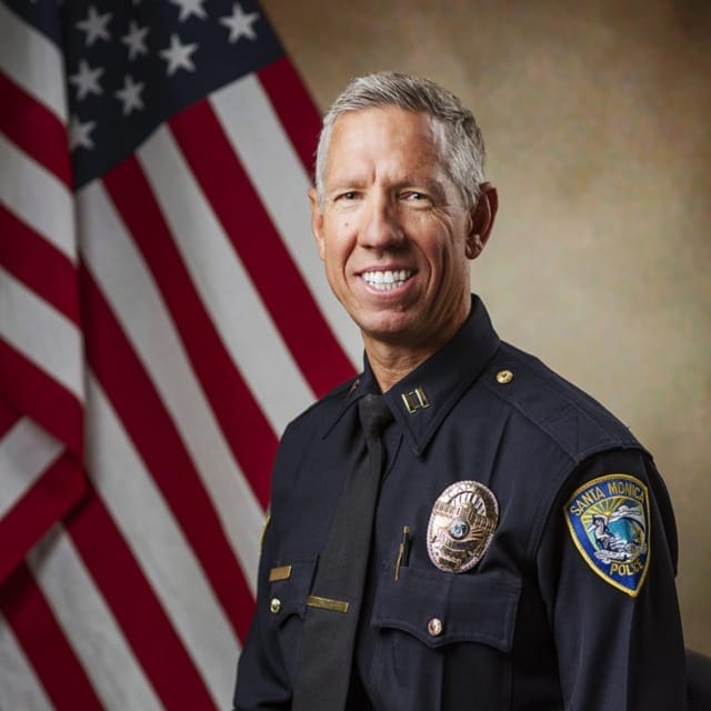 Police officer in uniform sitting in front of an American flag