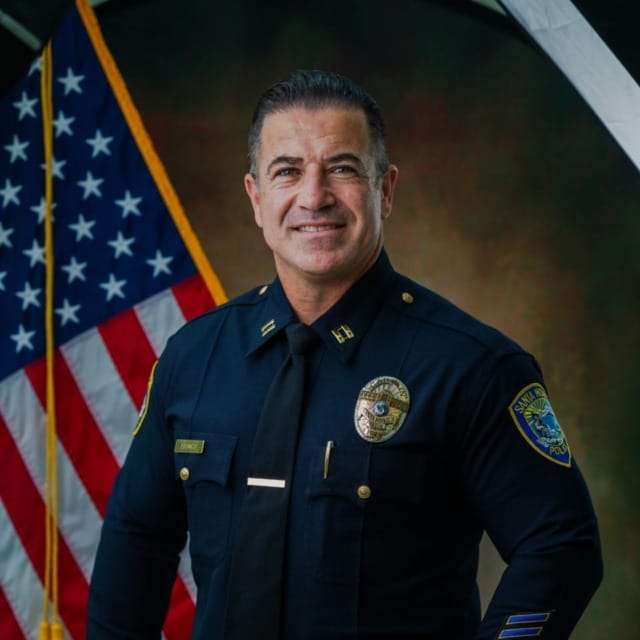 Police officer in uniform smiling in front of an American flag背景