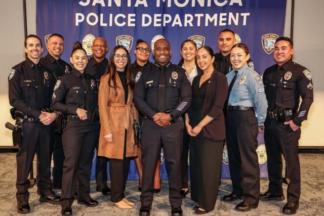 Group photo of Santa Monica Police Department officers and staff standing together in front of a department banner.